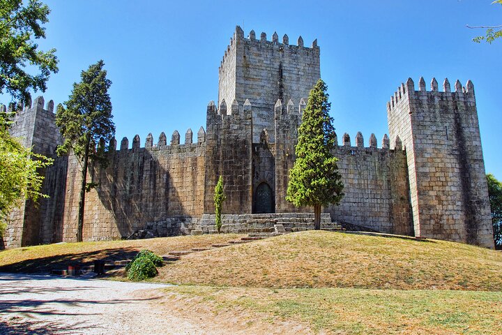 an old stone building with Guimarães Castle in the background